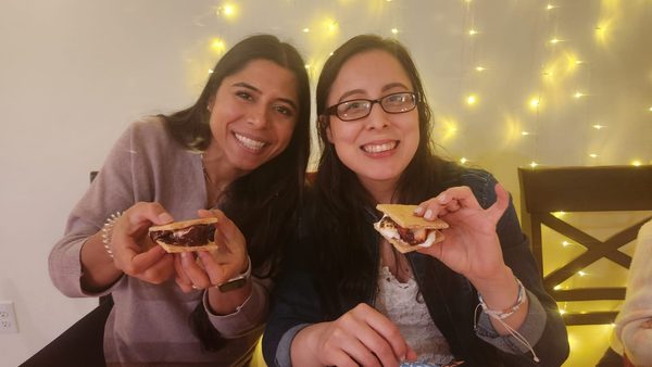 Members enjoying s'mores under string lights at a fellowship evening